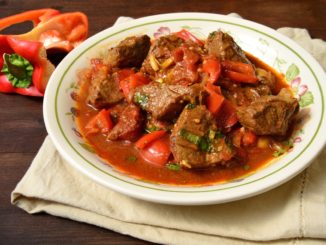 Мякоть свинины промыть, нарезать небольшими кубиками. Лук мелко нарезать и слегка обжарить в сковороде на подсолнечном масле, накрыв крышкой. Мясо положить в порционные глиняные горшочки, добавить лук, молотый красный перец, соль, влить немного воды и поставить в духовку. Тушить при температуре 160 °С 20 мин. Когда мясо будет почти готово, добавить нарезанный ломтиками перец, очищенные от кожицы и нарезанные кубиками помидоры и смешанный с мукой йогурт, поставить в духовку. При подаче на стол сбрызнуть гуляш лимонным соком.